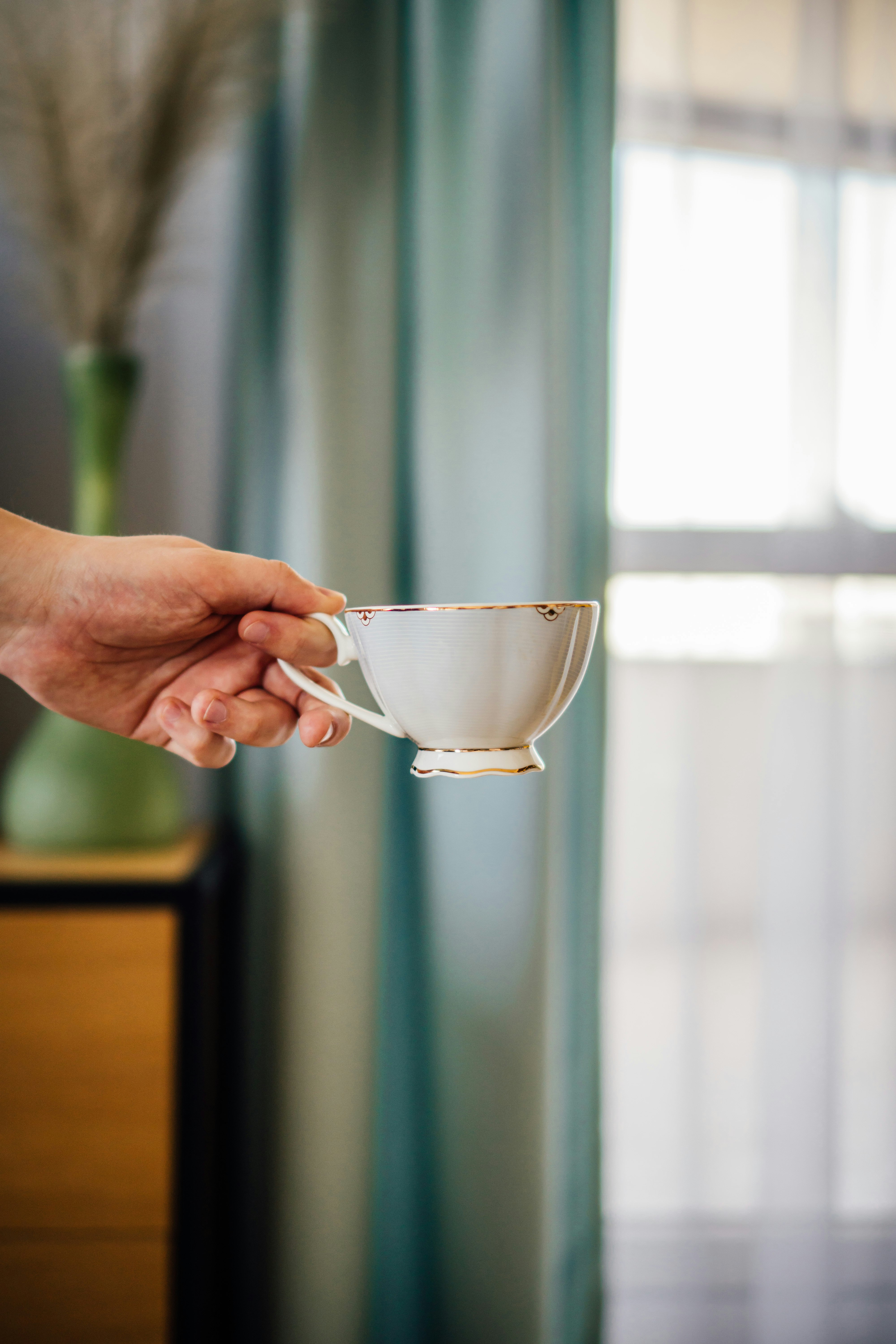 person holding white ceramic teacup